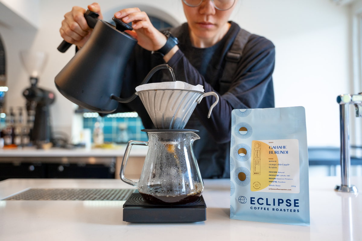Barista brewing Gahahe Burundi specialty coffee using a pour-over dripper and gooseneck kettle at Eclipse Coffee Roasters.